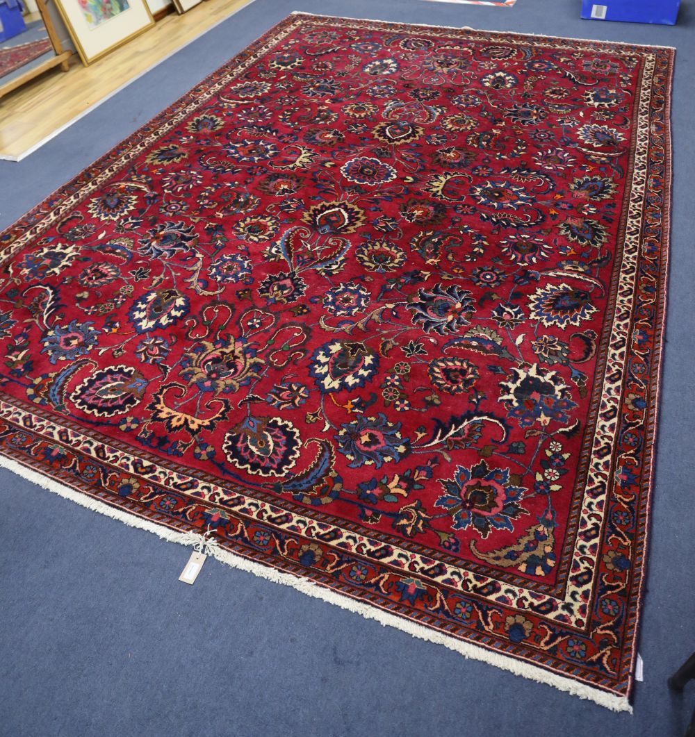 An Azerbaijan Tabriz rug having stylised foliate design on a claret field with two-row border and guard stripes, 327cm x 230cm